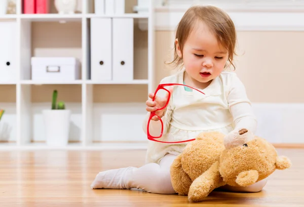 Chica feliz jugando con su osito de peluche y gafas — Foto de Stock