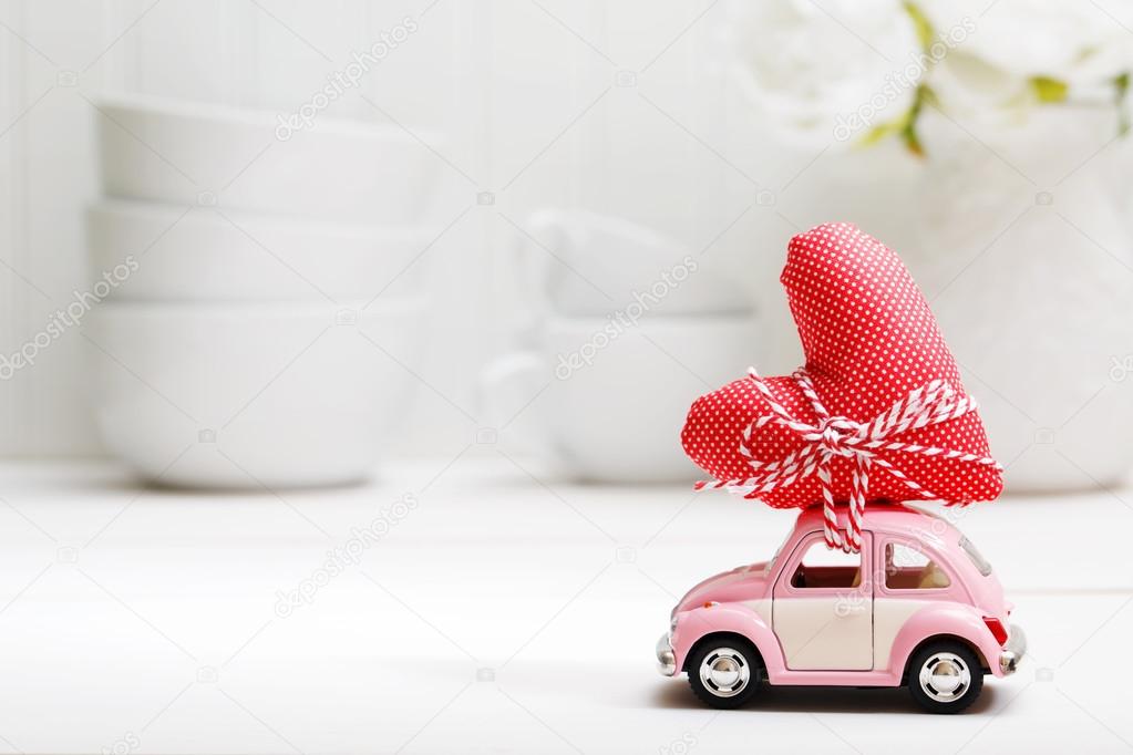 Miniature car carrying red heart cushion