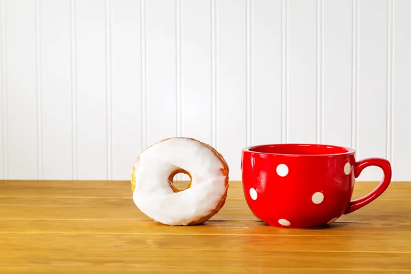木製のテーブルに赤いマグカップとドーナツ — ストック写真