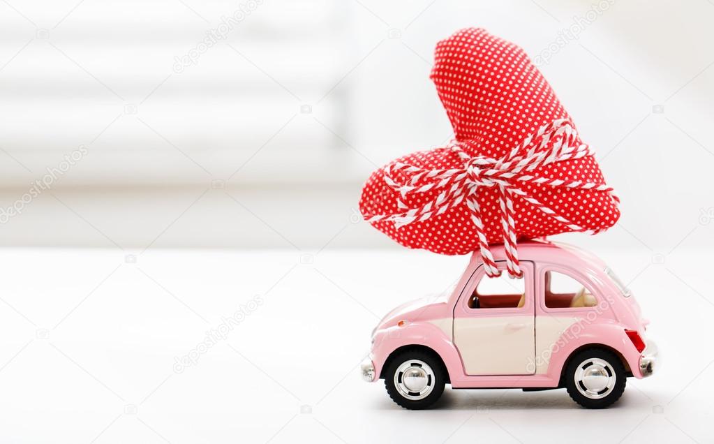 Miniature car carrying red heart cushion 