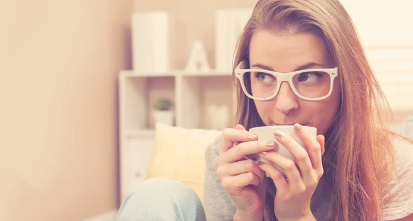 Genç kadın onu kanepeye kahve içme — Stok fotoğraf