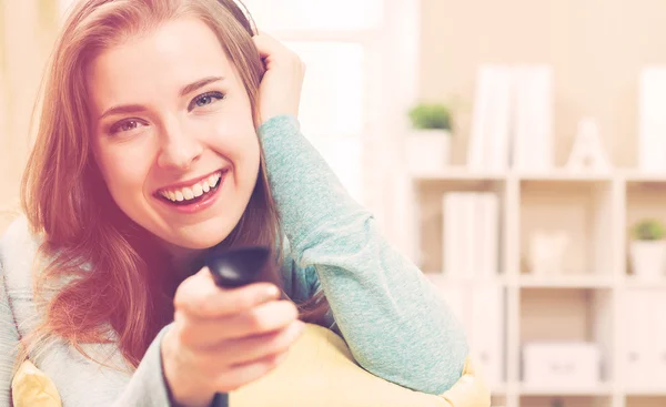 Mujer joven sonriendo mientras ve la televisión — Foto de Stock