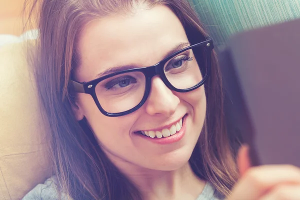 Jonge vrouw lezen van een e-boek op haar bank — Stockfoto