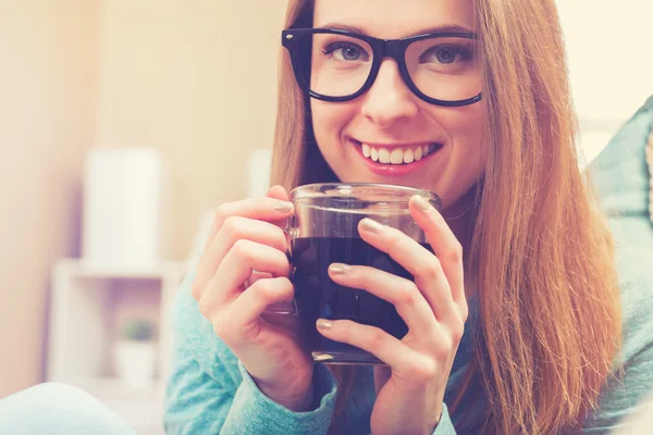 Jonge vrouw drinken koffie op haar bank — Stockfoto