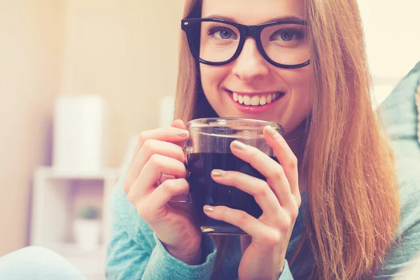 若い女性彼女のソファでコーヒーを飲む — ストック写真