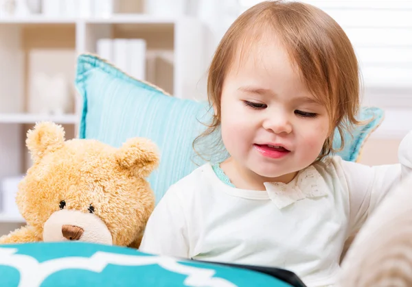 Peuter meisje met haar teddybeer en tablet pc — Stockfoto