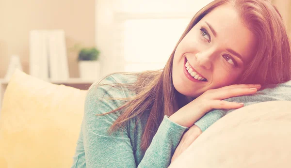 Mladá žena se usmívá ve svém obývacím pokoji — Stock fotografie