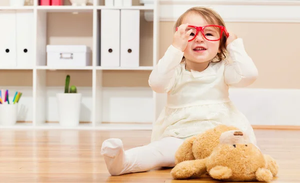 Dívka si hraje s ní medvídek a brýle — Stock fotografie
