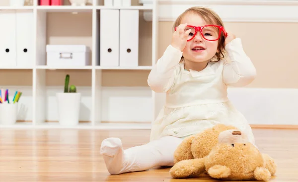 Meisje speelt met haar teddy beer en glazen — Stockfoto