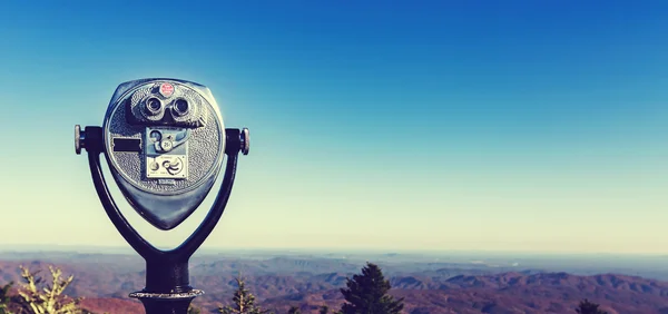 Coin-operated binoculars looking out over a mountain landscape