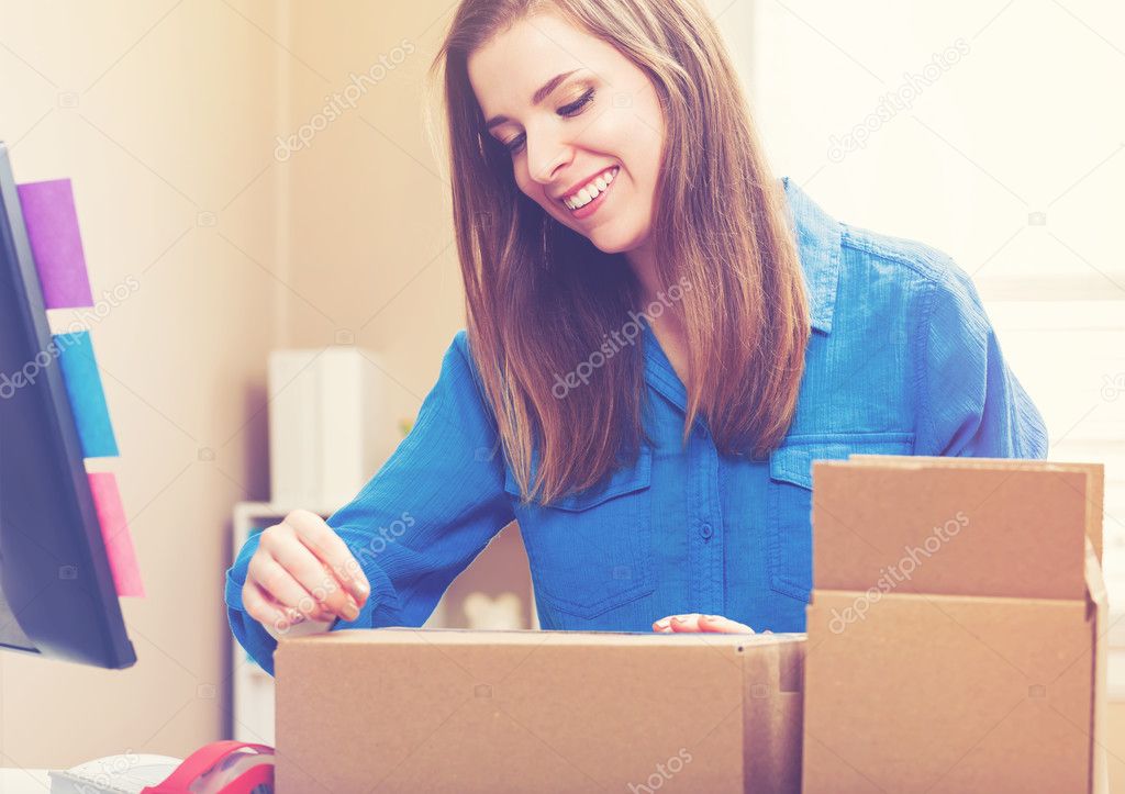 Young woman taping boxes to be shipped 