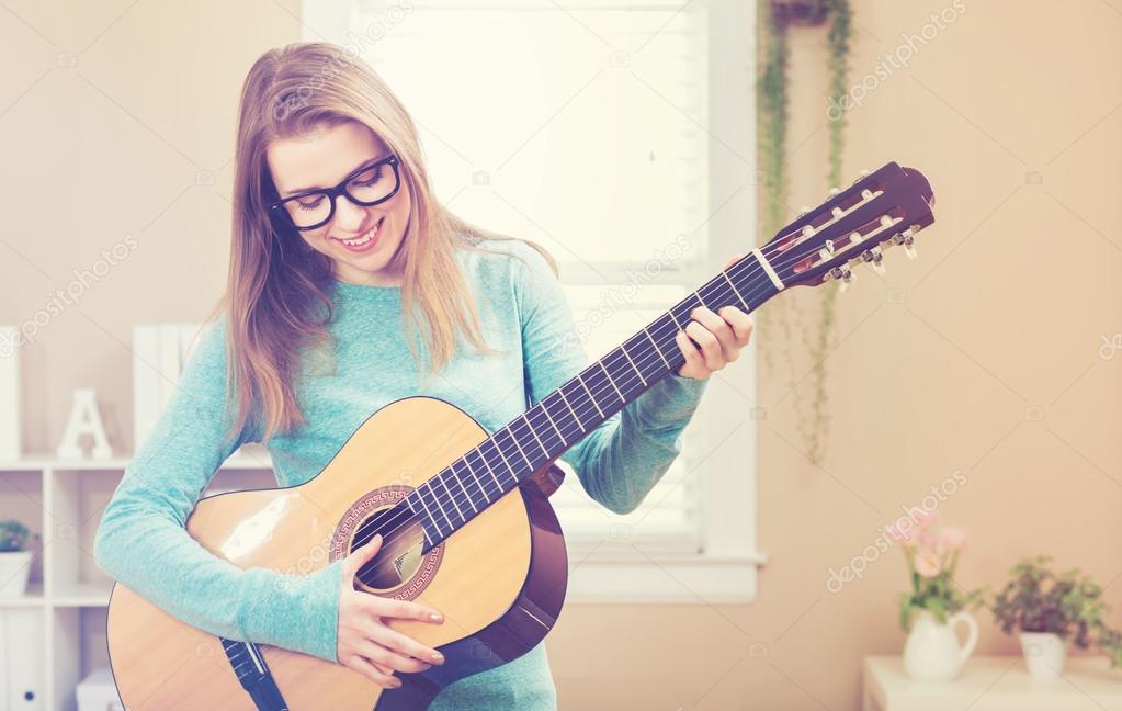 Happy young woman playing guitar 