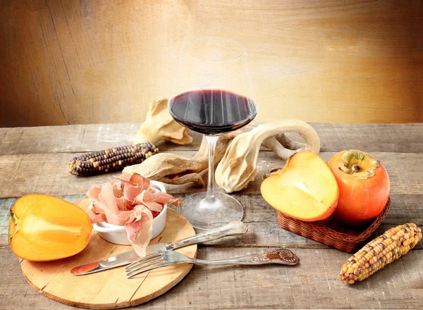 winter gourmet composition with red wine, persimmon, Parma ham,s
