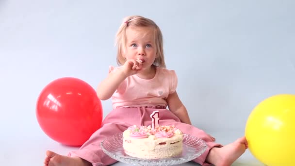 a kis kék szemű lány megünnepli az első születésnapját olyan stílusban törje össze a tortát és megkóstolja az első szülinapi tortáját.