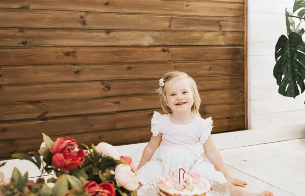 little beautiful blue-eyed girl celebrates her first birthday in the style smash a cake and she tastes her first birthday cake