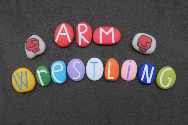 Bilek güreşi, spor adı siyah volkanik kumların üzerine çok renkli taş harflerle yazılmış.