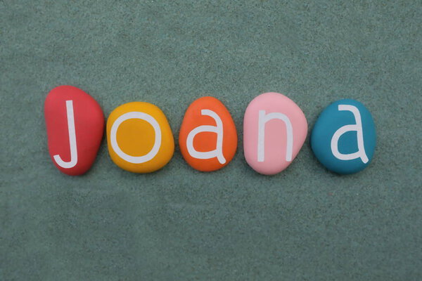 Joana, португальское женское имя, составленное из разноцветных каменных букв на зеленом песке