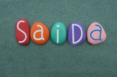 Saida 'nın kutlaması, kadın Arap ismi yeşil kumların üzerine çok renkli taş harflerle yazılmış.