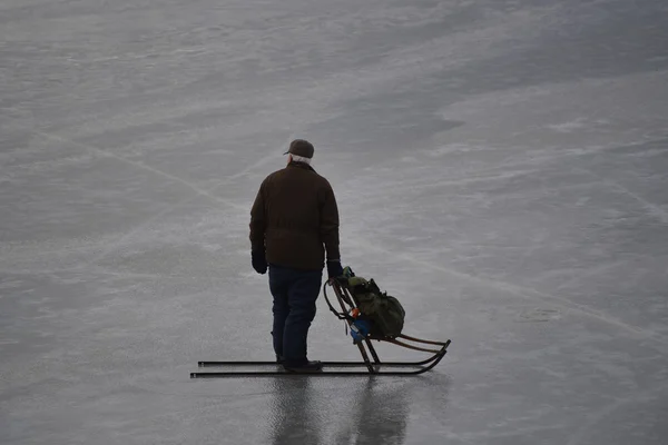 Old man with sledge over a frozen lake