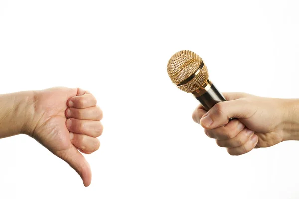 El micrófono dorado al alcance de la mano y el pulgar hacia abajo gesto. Concepto amarillo de información de chismes. espacio de copia — Foto de Stock