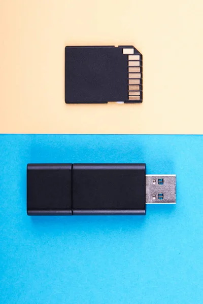 Clé USB et carte mémoire micro sd sur fond bleu et jaune. différents types de périphériques de stockage portables. concept de magasin de données — Photo