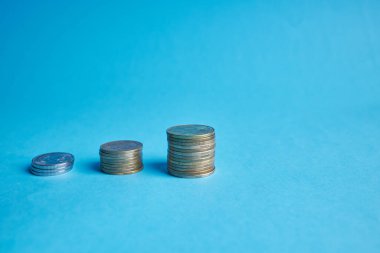 Bozuk paralar mavi arkaplanda fotokopi alanı ile istiflenir. Yatırım konsepti bankacılık kavramsal