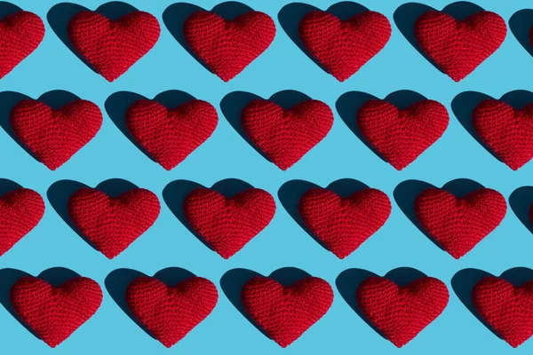 Wzór tekstury czerwonych serc wełnianych z twardymi cieniami na niebieskim tle. Patrząc z góry. koncepcja miłości — Zdjęcie stockowe