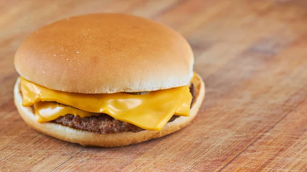 Vékony sajtburger vagy hamburger egy fából készült táblán átlós vonalak hátterével.szelektív fókusz. Másolás. széles termés — Stock Fotó