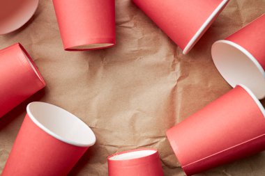 Kağıt zemin üzerinde tek kullanımlık kırmızı bardaklar yığını. Çevre dostu kavram. Yukarıdan bak. arkaplan