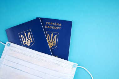 Mavi arka planda yüz maskesi olan Ukrayna pasaportu. kopyalama alanı. covid-19 seyahat ve turizm kavramı