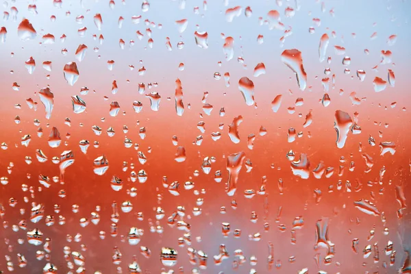 Gotas de chuva em vidro sobre fundo colorido calmo. fundo abstrato vermelho — Fotografia de Stock