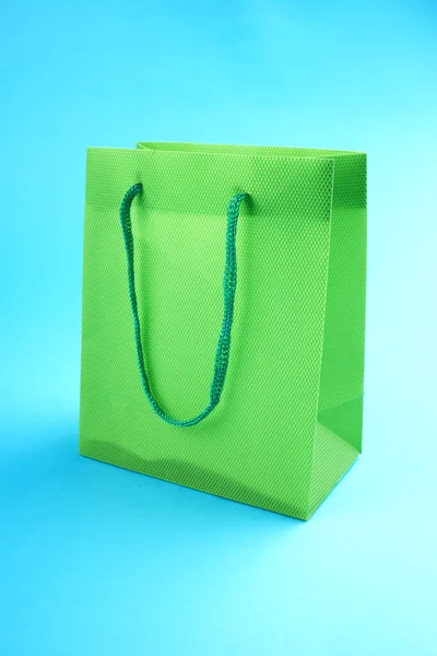 Saco de compras verde vazio sobre fundo azul. conceito de compras e venda — Fotografia de Stock