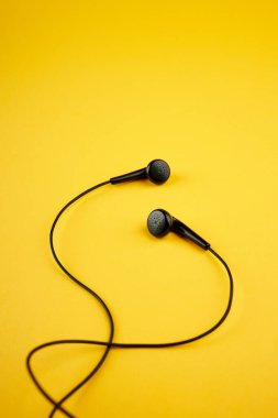 Siyah kulaklıklar sıcak sarı arka planda izole edilmiş. müzik yaşam tarzı konsepti. kopyalama alanı. düz yat