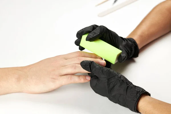 Manicura durante el trabajo usando uñas de buff. un proceso de manicura del hombre. una persona caucásica irreconocible haciendo servicio de uñas en el salón de spa. — Foto de Stock