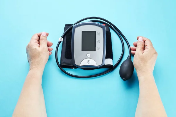 Měření krevního tlaku s elektronickým zdravotnickým zařízením přes modré pozadí — Stock fotografie