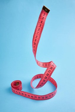 Kilo kaybı ölçüm konsepti. Kırmızı santimetre mavi arkaplan üzerinde dengeleniyor