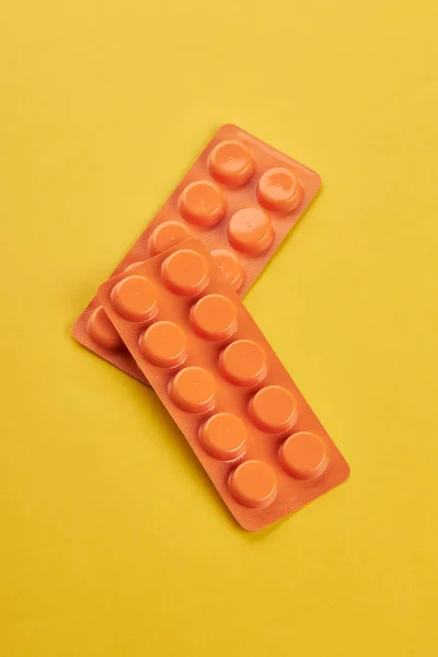 Concepto de bienestar médico. pastillas de color naranja sobre un fondo amarillo. espacio de copia. mínimo —  Fotos de Stock