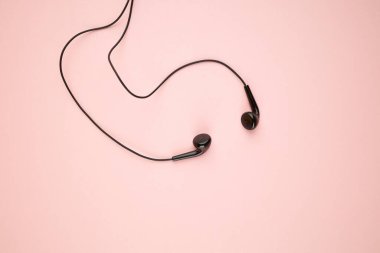 Pembe pastel arka planda izole edilmiş siyah kulaklık. Düz yat. Uzay boşluğu. müzik minimalizmi