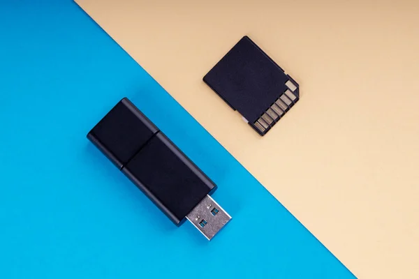 Usb flash y tarjeta de memoria SD sobre fondo azul y amarillo. diferentes tipos de dispositivos de almacenamiento portátiles. concepto de almacén de datos — Foto de Stock