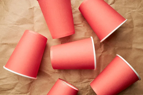 Sterta jednorazowych czerwonych kubków papieru na papierowym tle. ekologiczna koncepcja. Spójrz z góry. tło — Zdjęcie stockowe