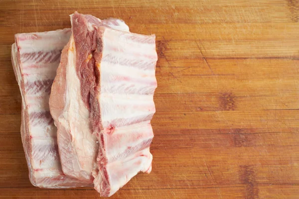 Свежие сырые свиные ребрышки на деревянном фоне. две части. ингредиент для мясной кухни — стоковое фото