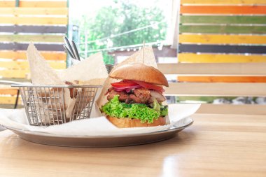 Taze tavuk lezzetli burger ve arkasında patates. Açık havada.