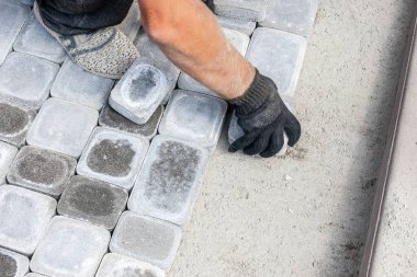 İşçiler yeni tuğlalar ya da patikaya beton bloklar kurarlar. Yol onarımı için döşeme döşemeleri