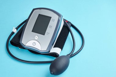 Mavi arka planda elektronik tıbbi cihazla kan basıncını ölçüyorum. Boşluğu kopyala