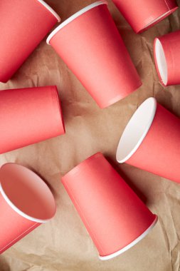 Kağıt zemin üzerinde tek kullanımlık kırmızı bardaklar yığını. Çevre dostu kavram. Yukarıdan bak. arkaplan