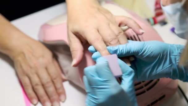 Manicura pulir y limar las uñas a la anciana cliente femenino. Mujer caucásica de 50 años en el salón de manicura. concepto de tratamiento de belleza — Vídeo de stock