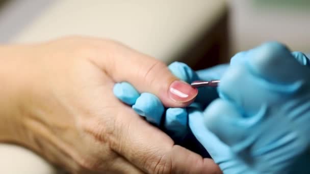 Manicure aplicação de goma laca ou esmalte unha para pessoa idosa do sexo feminino. mulher branca de 50 anos no procedimento de salão de manicura. conceito de cuidado de unhas de manicure — Vídeo de Stock