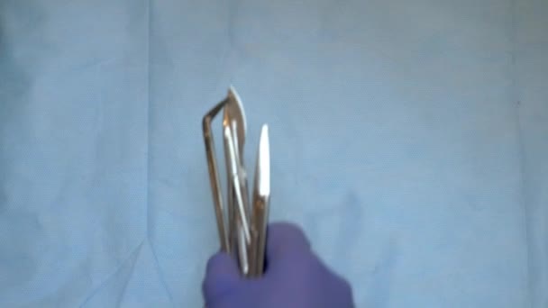 Mehrere chirurgische Instrumente auf blauem Tisch über der Ansicht. Chirurg legte chirurgisches Werkzeug auf Tischplatte ab — Stockvideo