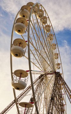 Dönme dolaba yakından bakmak, aynı zamanda büyük tekerlek olarak da bilinir, popüler bir panayır eğlencesi. Arkaplanı mavi bulutlu bir gökyüzü oluşturur