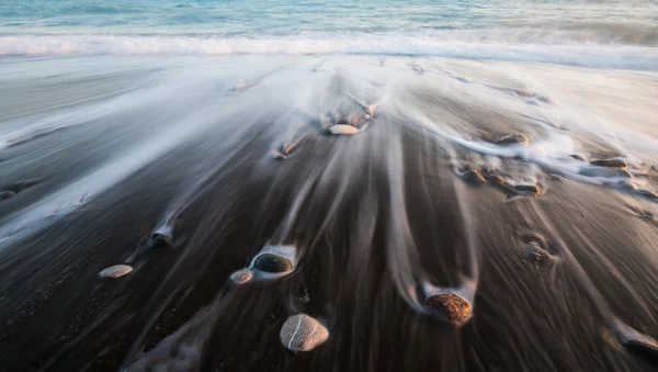 Kiezels in het strand en het stromende zeewater — Stockfoto